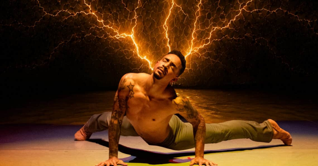 A person performing with a dramatic background featuring lightning.